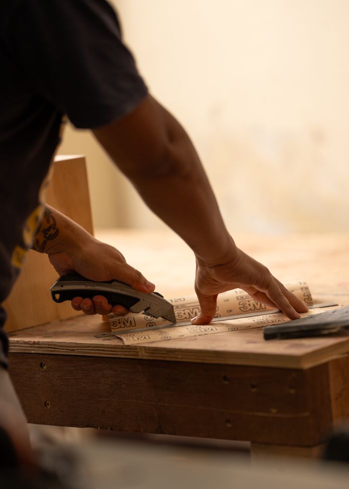 A skilled woodworker uses a utility knife to cut wood with precision on a workbench.