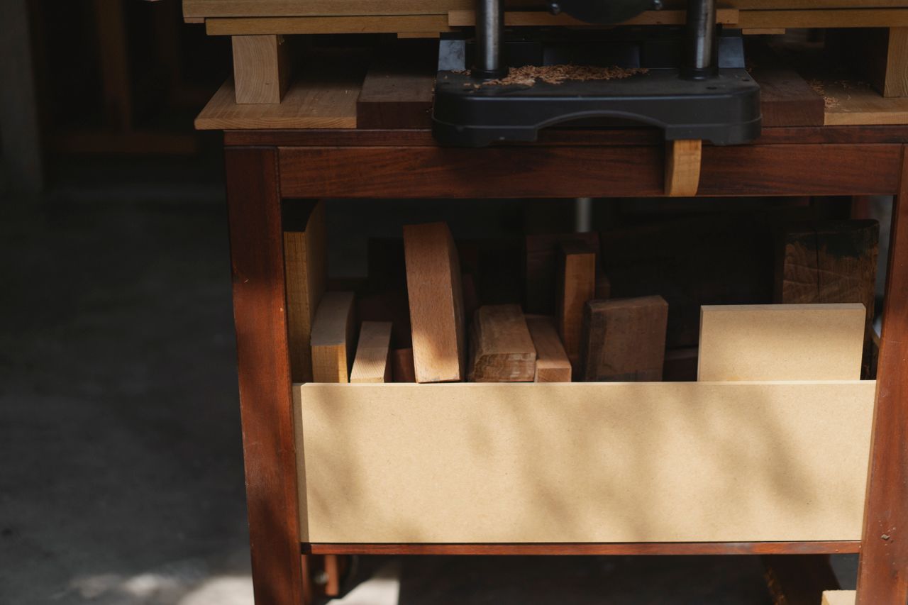 Professional electric equipment for woodwork and shavings above different wooden pieces in workshop in daytime