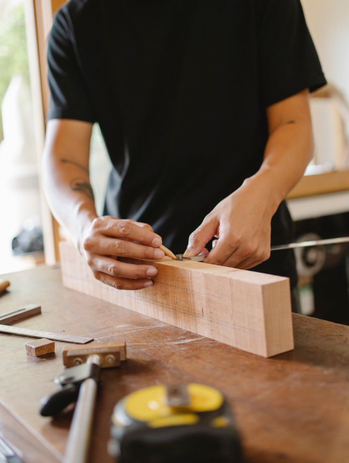 Crop unrecognizable male joiner making sign on wooden plank with pencil while making handicraft in workshop
