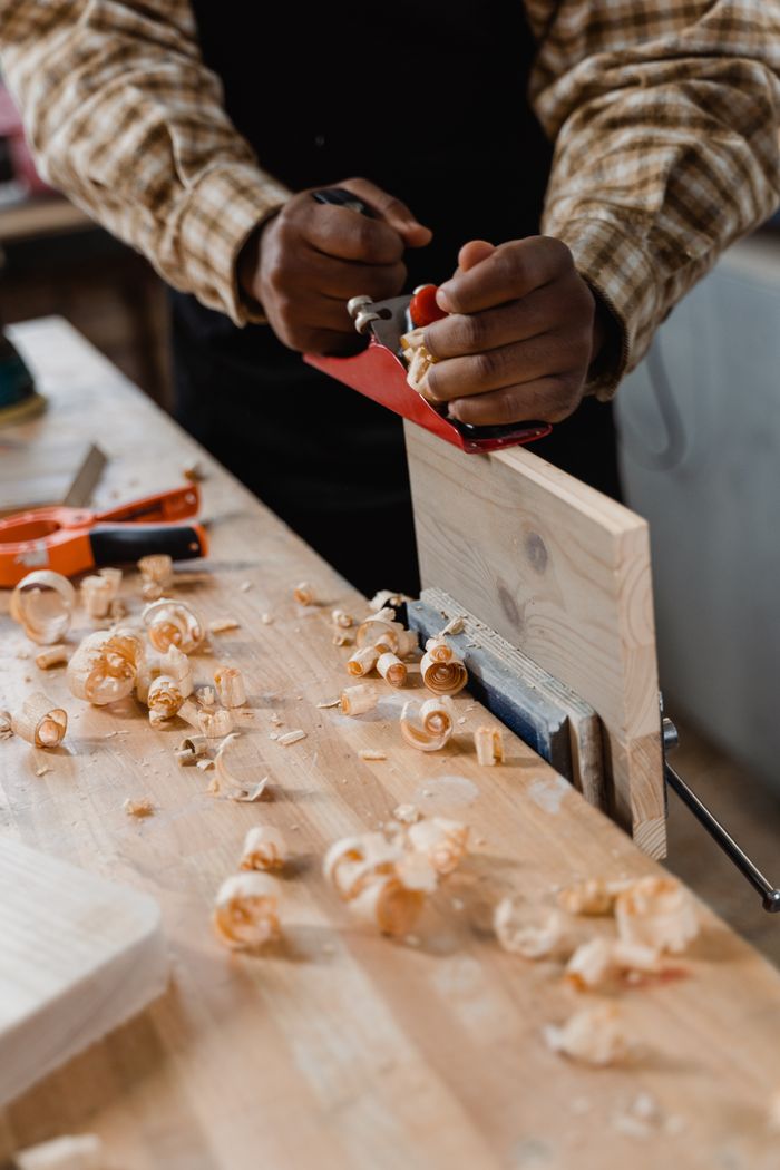 Carpenter shaping wood with planer in a workshop. Hands-on craftsmanship and skills.